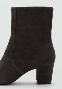 Bottine en daim noir avec un bout arrondi, une texture lisse et un talon carré. Présente une silhouette élégante et des détails de couture minimalistes.