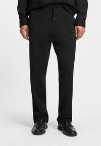 Schwarze Nadelstreifenhose aus leichtem Stoff mit elastischem Bund und Kordelzug, geraden Beinen und glatter Textur.