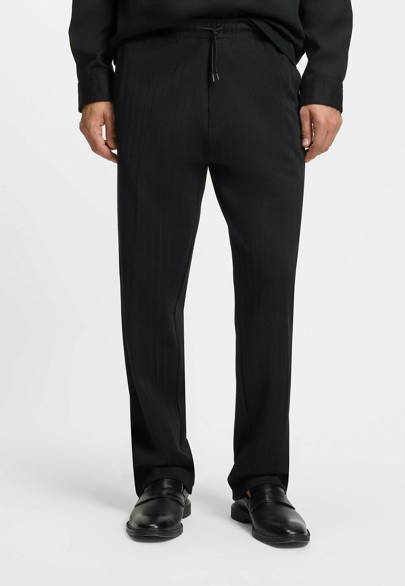 Schwarze Nadelstreifenhose aus leichtem Stoff mit elastischem Bund und Kordelzug, geraden Beinen und glatter Textur.