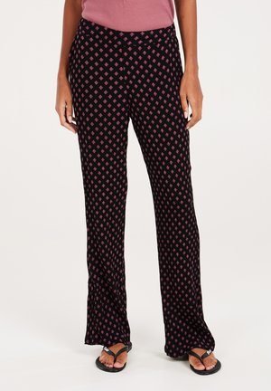 Black patterned pants featuring a diamond design in pink. Flared leg silhouette with a wide waistband, made from a soft, stretchy material.
