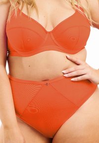 Oranssi alusvaatesetti, joka sisältää tukevan rintaliivimallin, jossa on ympäryskaari, sekä korkeavyötäröiset alushousut, molemmat tehty sileästä ja tekstuurillisesta kankaasta.
