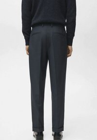 Pantalon coupe ajustée bleu foncé avec un devant plissé, deux poches arrière et un ourlet revers. Tissu lisse avec une coupe structurée.