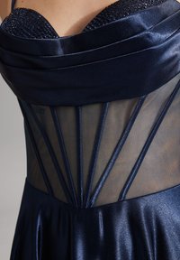 Abito da sera blu navy con corpetto in satin, pannelli in rete trasparente e cuciture decorative. Il corpetto presenta un design arricciato con decorazioni.
