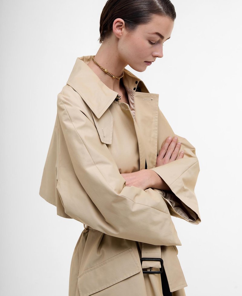 Beige Trenchcoat mit weit geschnittenem Kragen und übergroßen Ärmeln. Er verfügt über einen Gürtel mit einer rechteckigen Schnalle und hat eine glatte Textur.