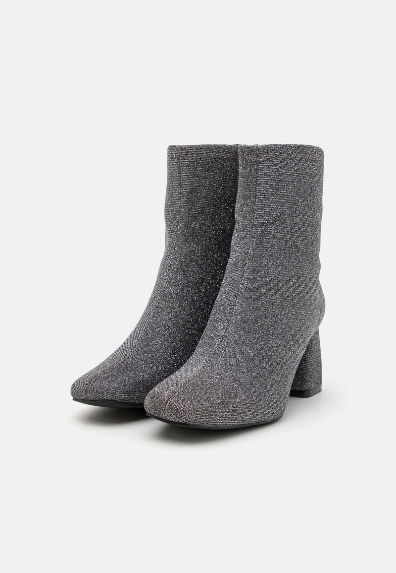 Paire de bottes mi-mollet gris pailleté avec bouts arrondis et talons blocs sur fond blanc.