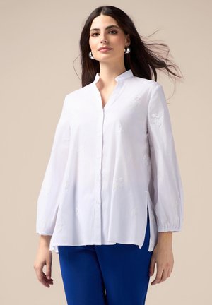Camicia bianca a maniche lunghe con colletto alla cinese, dettagli ricamati, maniche lunghe con polsini elasticizzati e orlo curvo.