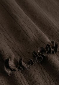 Rudas megztas audinys su griovelių tekstūra ir mažais raštais, turintis susiraukšlėjimą iš vienos pusės. Minkštas ir lengvas audinys.