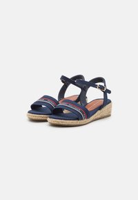 Marineblauwe wedge-sandalen met stoffen banden, verstelbare enkelriem en een met jute bedekte hak. Kenmerkt zich door rood-witte branding op de banden.