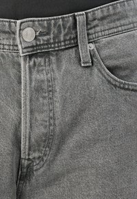Sive jeans iz denima z rahlo teksturirano površino, ki imajo kovinski gumb za zapiranje, zanke za pas in sprednje žepe.