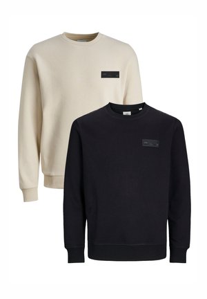 Zwei übereinander gestapelte Sweatshirts: eines in Creme mit einem Etikett, das andere in Schwarz mit einem Etikett. Beide verfügen über einen klassischen Rundhalsausschnitt und gerippte Bündchen. Weicher Stoff.