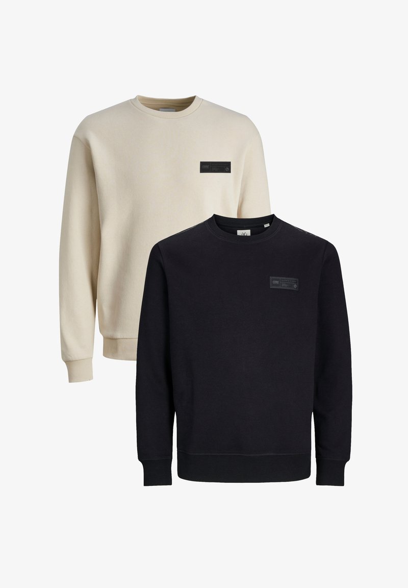 Zwei übereinander gestapelte Sweatshirts: eines in Creme mit einem Etikett, das andere in Schwarz mit einem Etikett. Beide verfügen über einen klassischen Rundhalsausschnitt und gerippte Bündchen. Weicher Stoff.