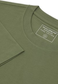 Oliwkowa, oversize koszulka z czystej bawełny, z okrągłym dekoltem, krótkimi rękawami oraz metką z rozmiarem M. Gładka faktura i widoczne szwy.