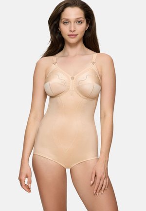 Kvinde iført nude formende bodysuit med blomsterblonde-detaljer, justerbare stropper og en glat pasform, stående mod en hvid baggrund.
