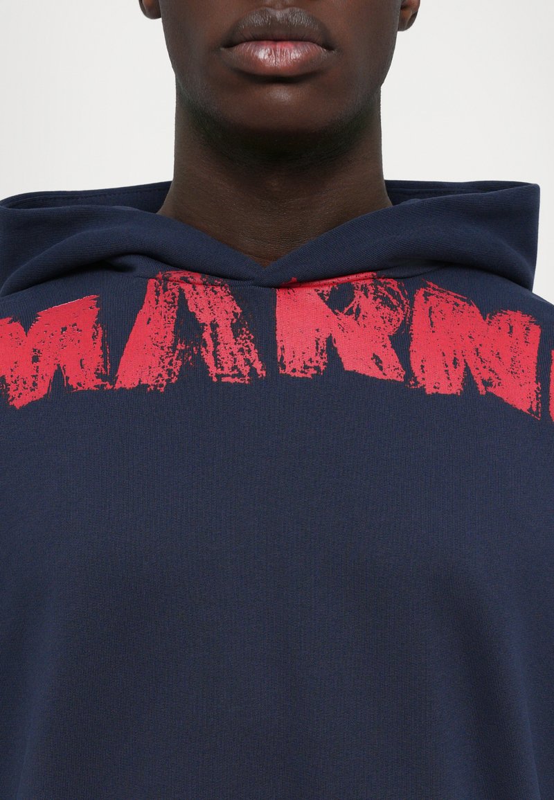 Navy hoodie with a large, distressed red print reading "WARM" on the front. Features a drawstring hood and soft fabric texture.
