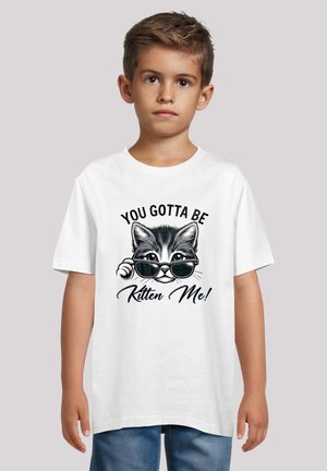 White T-shirt featuring a graphic of a kitten wearing sunglasses. Text reads "YOU GOTTA BE Kitten Me!" in black. Short sleeves, casual fit.