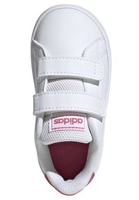 Baskets blanches avec tige en synthétique, sangles Velcro, col rembourré, languette en mesh, et accent rose sur la semelle intérieure et le logo.