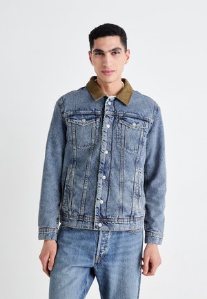 Denimjas met een vervaagde blauwe wassing, een bruine corduroy kraag, een sluiting met knopen aan de voorkant, twee borstzakken en opvallende stikseldetails.
