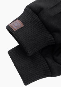 Schwarze Handschuhe aus weichem, strukturiertem Fleece-Material mit gerippten Bündchen. Ein kleines braunes Logopatch ist am Handgelenk sichtbar.