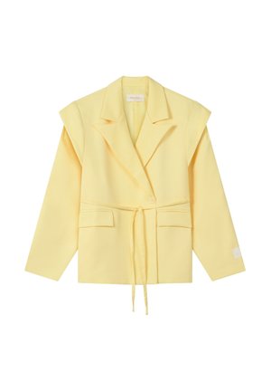 Blazer sur mesure jaune clair avec épaules rembourrées, fermeture à bouton unique, poches avant et ceinture nouée à la taille sur fond blanc.