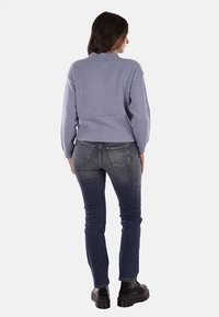 Maglione azzurro chiaro con colletto alto, lavorazione a maglia testurizzata e orlo a costine, abbinato a jeans blu scuro e stivali neri chunky.