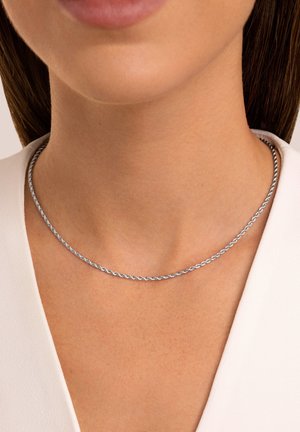 Collana in argento caratterizzata da un design intrecciato, una texture liscia e un leggero luccichio, posizionata sulla clavicola.