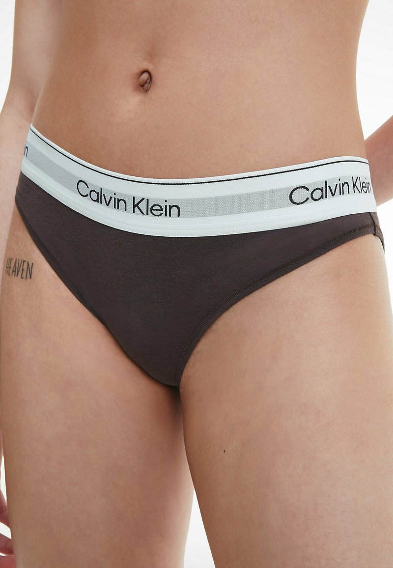 Bóxer de algodón marrón de Calvin Klein con cinturilla de logo en azul claro y negro, que presenta una textura suave y un estilo de bikini estándar.