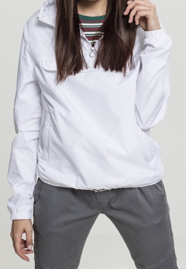 White nylon anorak with a zippered collar and elastic cuffs, paired with grey trousers. The anorak has a relaxed fit and a smooth texture.