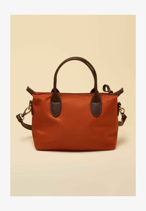 Rechteckige Handtasche in Rostfarbe mit dunkelbraunen Griffen und abnehmbarem Schulterriemen, vor einem beigen Hintergrund präsentiert.