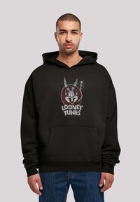 Svart hettegenser med Looney Tunes grafikk. Mykt materiale, avslappet passform, kengurulomme og ribbestrikkede mansjetter.