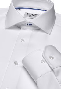 Weißes Slim-Fit-Hemd aus bügelfreiem Stoff, mit spitzem Kragen, blauen Akzenten in der Naht und perlfarbenen Knöpfen.