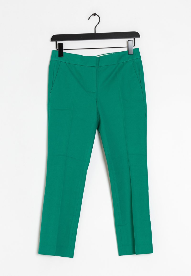 Pantalons taper verts avec une texture lisse, dotés de deux poches latérales et d'une fermeture éclair. Accrochés à un cintre en plastique noir.