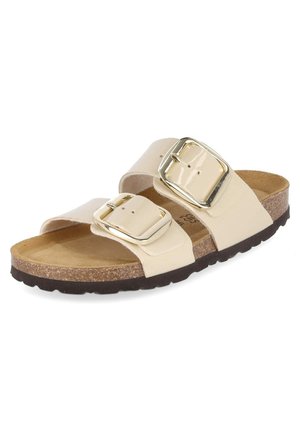Sandale beige avec deux larges brides réglables dotées de grandes boucles dorées, semelle intérieure en liège et semelle extérieure noire texturée.