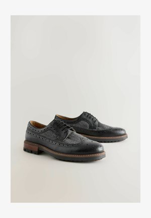 Black leather dress shoes with a textured herringbone pattern, brogue detailing, and a sturdy brown wooden heel.