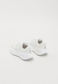 Paire de chaussures de course Nike ZoomX blanches avec tissu texturé et semelles épaisses et rembourrées sur fond blanc.