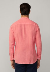Langsleeve shirt in fel koraal, gemaakt van linnen. Heeft een knoopmanchet en een gebogen zoom. De achterkant heeft een yoke-detail.