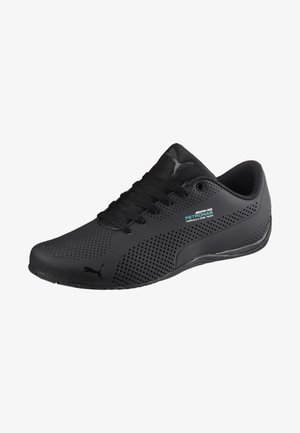 Baskets Puma noires avec un design perforé, des lacets noirs et un petit logo de l'équipe AMG Petronas de Formule 1 sur le côté.