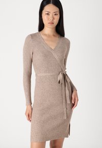 Robe enveloppante en tricot côtelé de couleur marron clair, dotée d'un décolleté en V, de manches longues, d'une taille ceinturée et d'une fente latérale pour une silhouette ajustée.