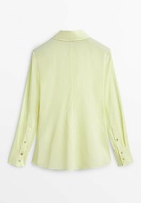 Camicia gialla chiaro a maniche lunghe con colletto, polsini abbottonati e taglio dritto. Tessuto liscio con una leggera lucentezza.