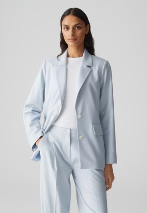 Hellblau maßgeschneiderte Blazer aus weichem Stoff, mit Reverskragen, doppelten Knöpfen und Seitentaschen, kombiniert mit passenden Hosen.