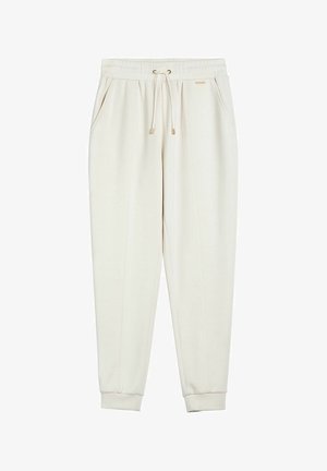 Ecru zwężane spodnie dresowe z elastycznym paskiem w talii, sznurkiem do ściągania, bocznymi kieszeniami i ściągaczami przy kostkach, z małą metalową metką marki.