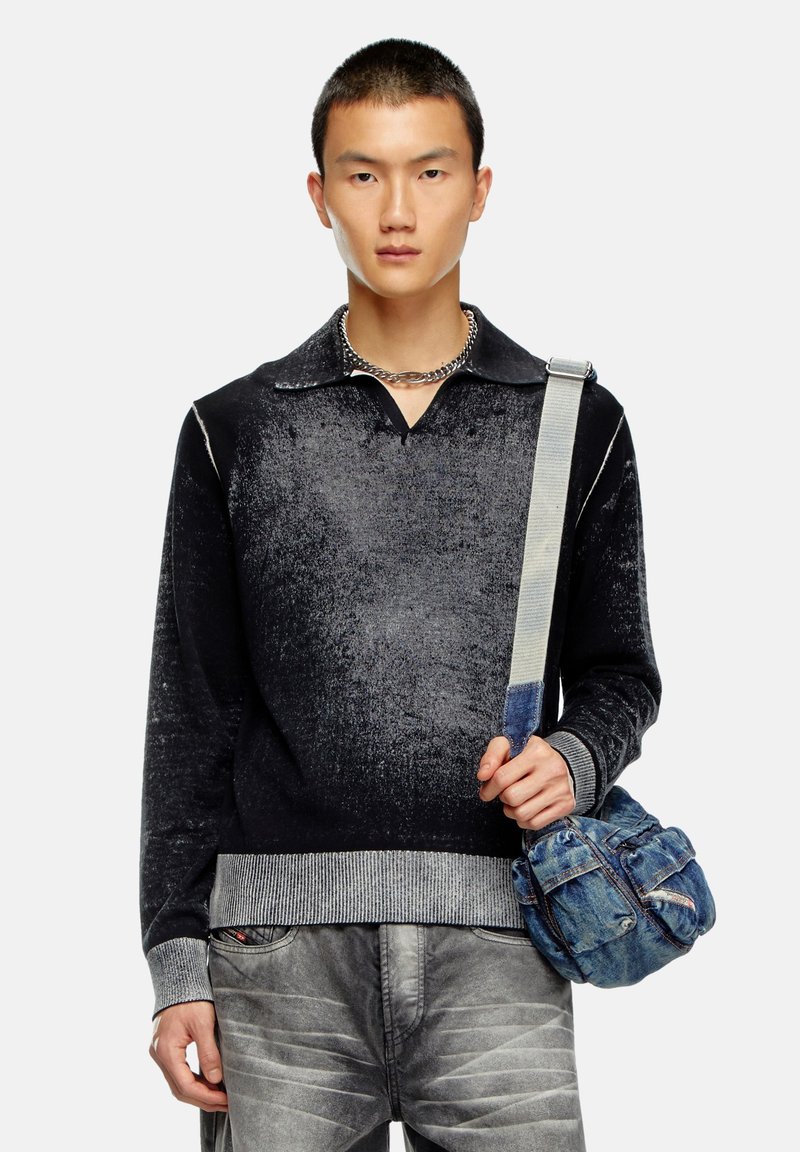 Pull en tricot dégradé noir avec un col et des poignets côtelés, associé à un jean gris clair déchiré et un sac bandoulière en denim bleu.