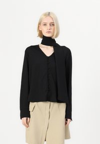 Camicia nera a maniche lunghe con abbottonatura davanti e sciarpa coordinata, caratterizzata da righe verticali e un tessuto morbido e texturizzato.