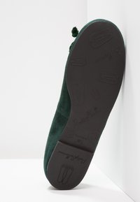 Ballet flat verde in suede con suola in gomma nera. Presenta una punta arrotondata e pompon decorativi sulla parte anteriore. Marchio in rilievo sulla suola.
