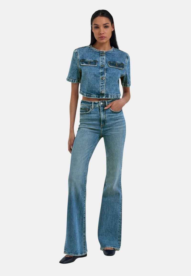 Giacca di jeans ritagliata con maniche corte, due tasche frontali e chiusura a bottoni; abbinata a jeans svasati a vita alta di colore azzurro chiaro.