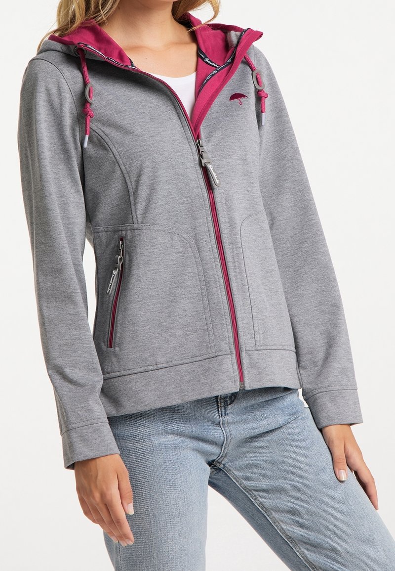 Veste grise avec fermeture éclair, bordure intérieure de capuche rose. Comprend des poches latérales, une capuche avec cordon de serrage, et une coupe slim. Texture du tissu douce.