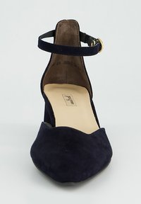 Chaussure à talons hauts en daim bleu marine avec bout ouvert, bride à la cheville et accessoires dorés. Dotée d'un bout pointu et d'une doublure intérieure lisse.