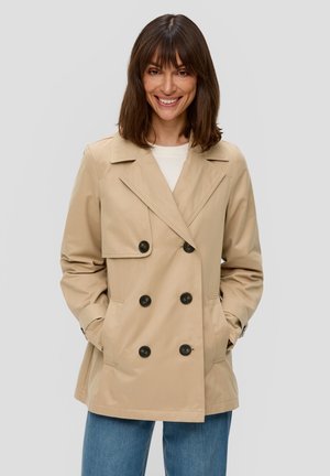 Trench coat beige doppiopetto con bottoni neri, ampi rever e tasche laterali. Tessuto leggero con una texture liscia.