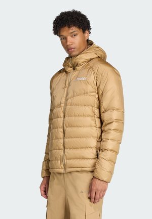Beige Puffer-Jacke mit Kapuze, ausgestattet mit einem gesteppten Design und glatter Textur. Enthält einen Frontreißverschluss und ein Logo-Detail auf der Brust.