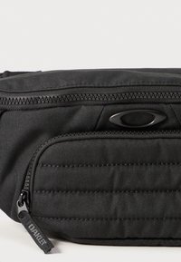 Schwarze Stoff-Taillentasche mit einer glatten Textur, rechteckiger Form, einem oberen Reißverschluss und einer vorderen Reißverschlusstasche mit gestepptem Design.