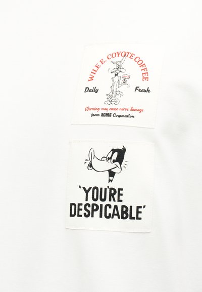 Ο Wile E. Coyote κρατάει μια πινακίδα με τη φράση «Αγάπησέ με!» με το κείμενο «WILE E. COYOTE COFFEE Καθημερινά Φρέσκο» και ο Daffy Duck λέει «ΕΙΣΑΙ ΑΗΔΙΑΣΤΙΚΟΣ».